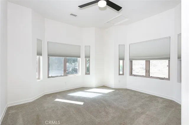 an empty room with windows and fan