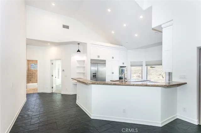 a kitchen with stainless steel appliances granite countertop a sink and a refrigerator
