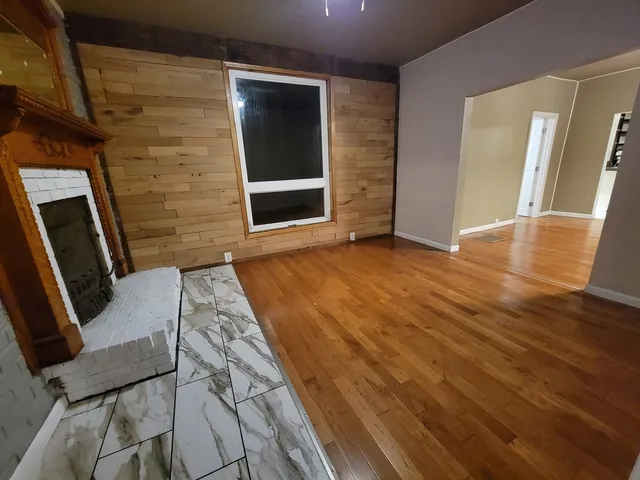 a view of an empty room with wooden floor and door