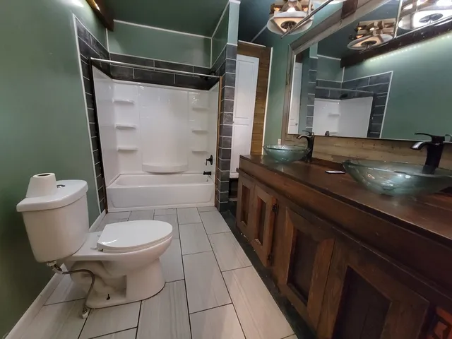 a bathroom with a granite countertop sink toilet a mirror and shower