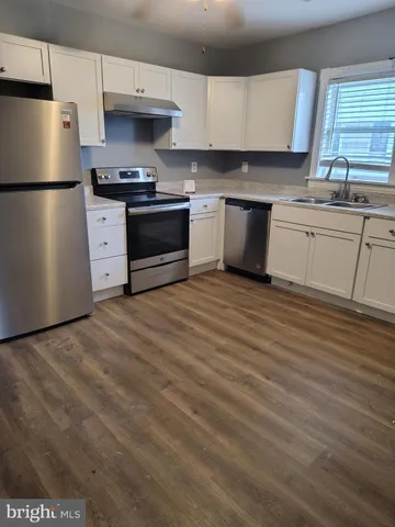 a kitchen with stainless steel appliances a sink a stove a refrigerator and cabinets