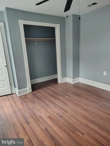 a view of an empty room with wooden floor and closet