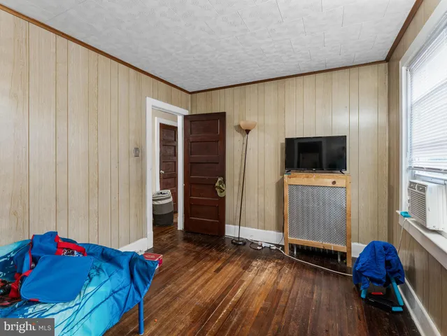 a living room with a bed furniture and a flat screen tv