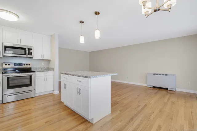 a kitchen with granite countertop white cabinets and stainless steel appliances