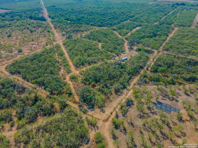 an aerial view of residential houses with outdoor space and trees