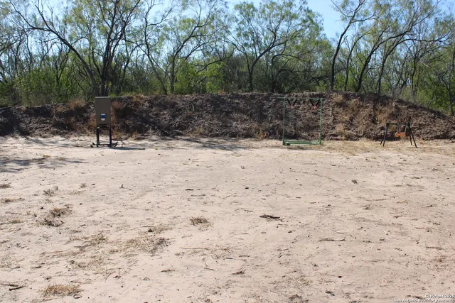 a view of a dry yard with trees in the background