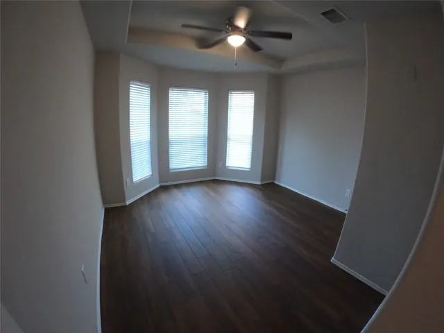 an empty room with wooden floor and windows