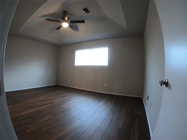an empty room with wooden floor and windows