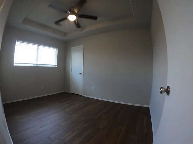 an empty room with wooden floor and a ceiling fan