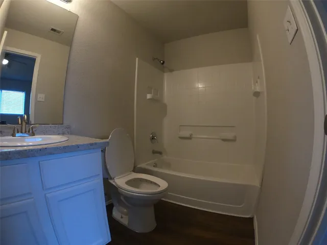 a bathroom with a toilet sink vanity granite and shower