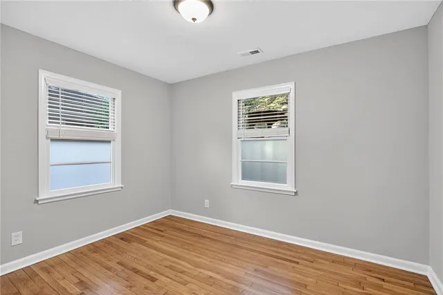 an empty room with wooden floor cabinet and windows