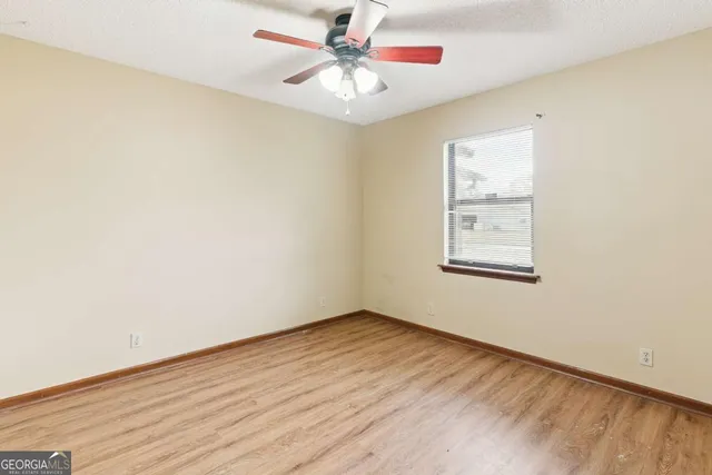 an empty room with a window and a fan