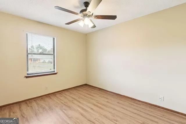 an empty room with a window and a ceiling fan