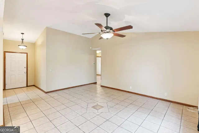 a view of an empty room and chandelier fan