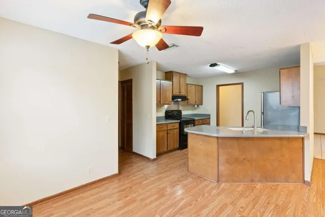 a large kitchen with a counter space a sink appliances and cabinets