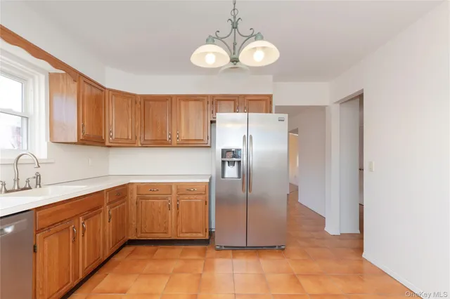 a kitchen with stainless steel appliances granite countertop a refrigerator a sink dishwasher and wooden cabinets with a granite countertops