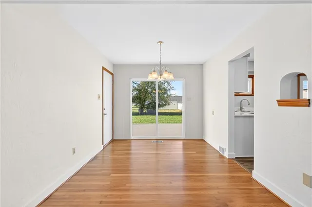 a view of an empty room with window wooden floor and a kitchen