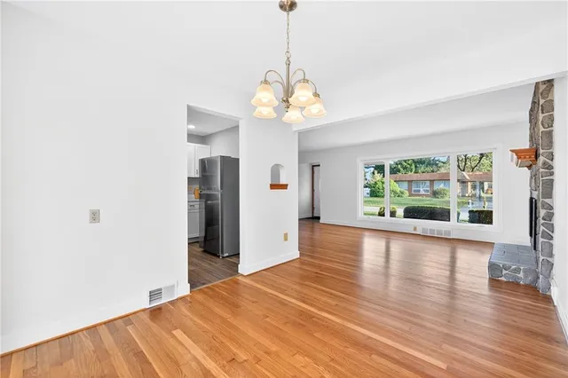 a view of a room with wooden floor chandelier and windows