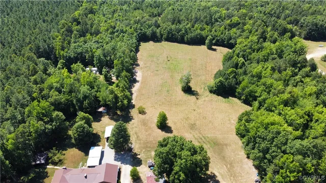 an aerial view of a house with a yard and trees all around