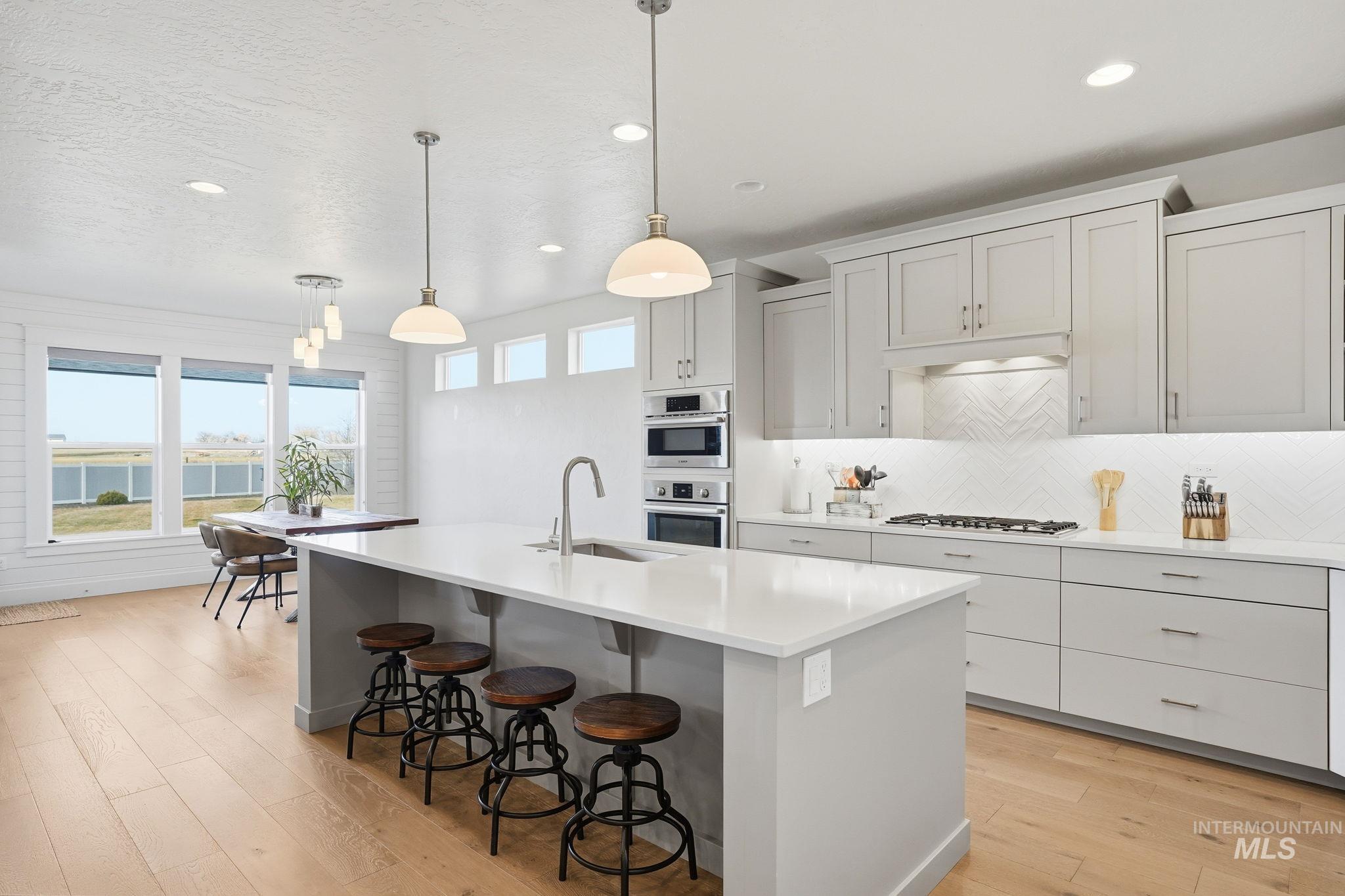 2301 Nordic Avenue Middleton, ID 83644 - Photo 10 of 50 Kitchen with decorative light fixtures, a breakfast bar, light wood finished floors, an island with sink, and oven