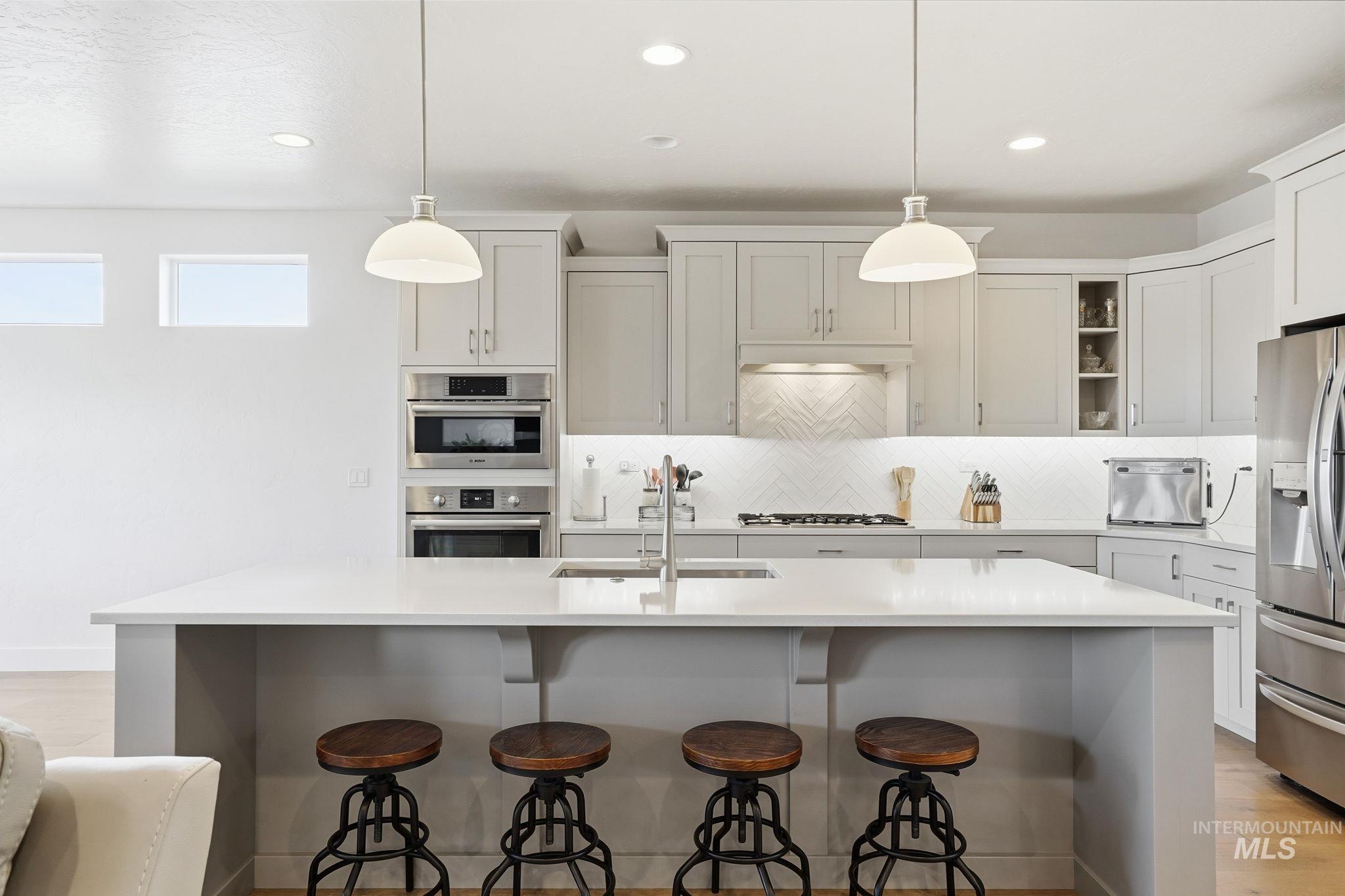 2301 Nordic Avenue Middleton, ID 83644 - Photo 11 of 50 Kitchen with light wood finished floors, an island with sink, stainless steel appliances, and decorative light fixtures