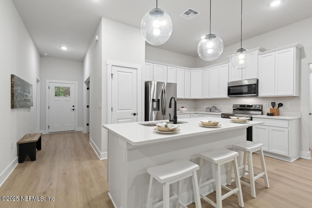 5124 Parete Road South Jacksonville, FL 32218 - Photo 20 of 42 a kitchen with stainless steel appliances a stove center island a refrigerator and a dining table with wooden floor