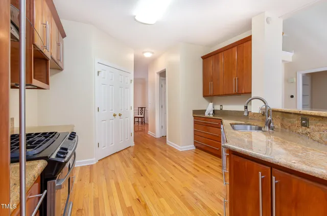 a kitchen with stainless steel appliances granite countertop wooden floor sink stove and granite counter top