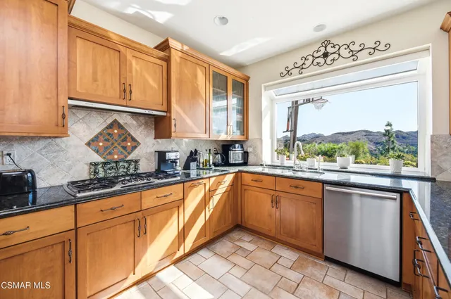 a kitchen with stainless steel appliances granite countertop a stove a sink and a microwave