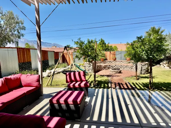 a view of a patio with table and chairs potted plants and a palm tree