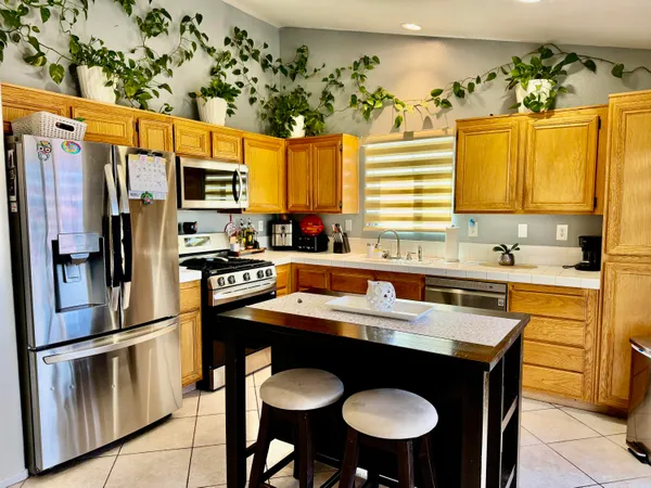 a kitchen with stainless steel appliances granite countertop a sink a stove a refrigerator and island