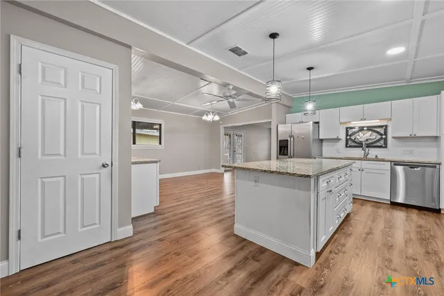a kitchen with stainless steel appliances granite countertop a white cabinets and wooden floors