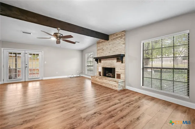 a view of an empty room with wooden floor fireplace and a window