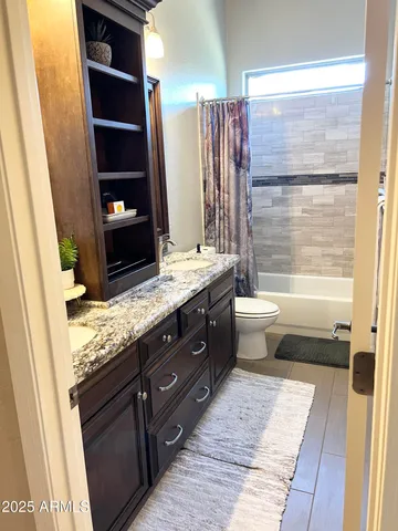 a bathroom with a granite countertop sink a toilet and shower