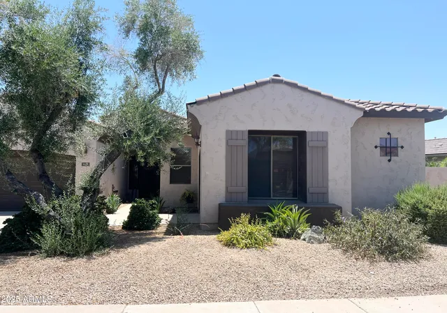 a view of a house with a small yard plants and a large tree