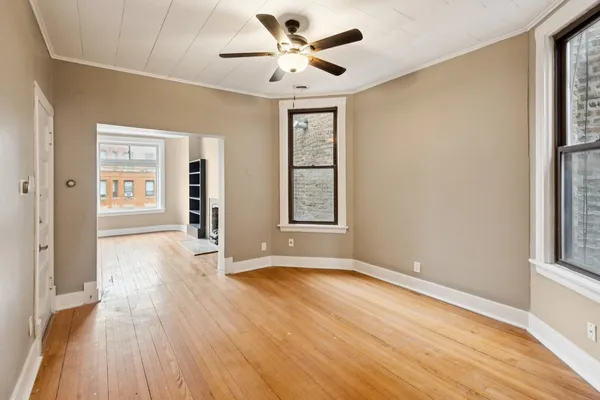 a view of an empty room with a window and wooden floor