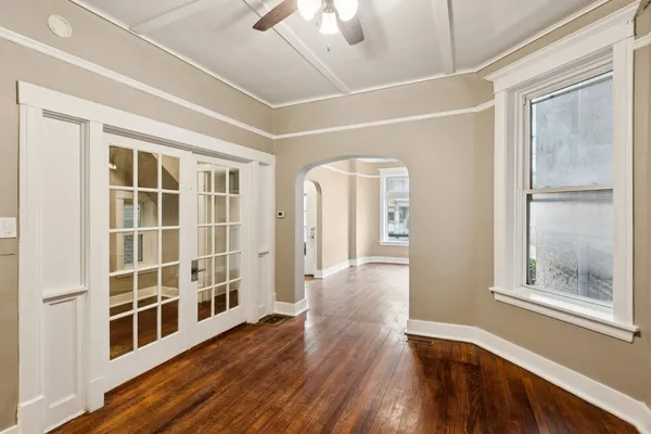 a view of an empty room with wooden floor and a window