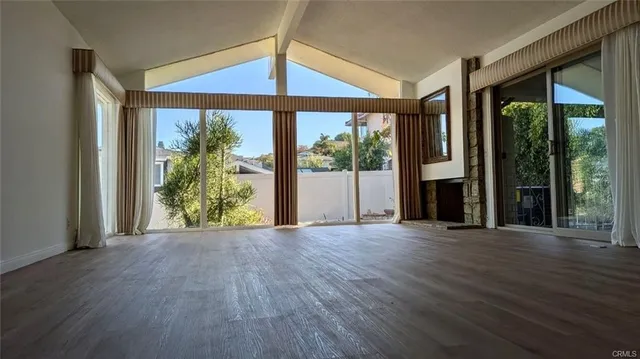 an empty room with wooden floor and a floor to ceiling window