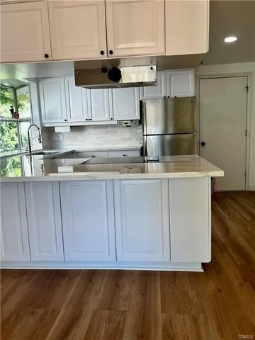 a kitchen with granite countertop a sink a stove and a wooden cabinets