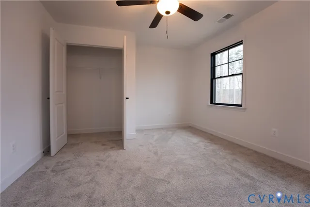an empty room with windows and ceiling fan