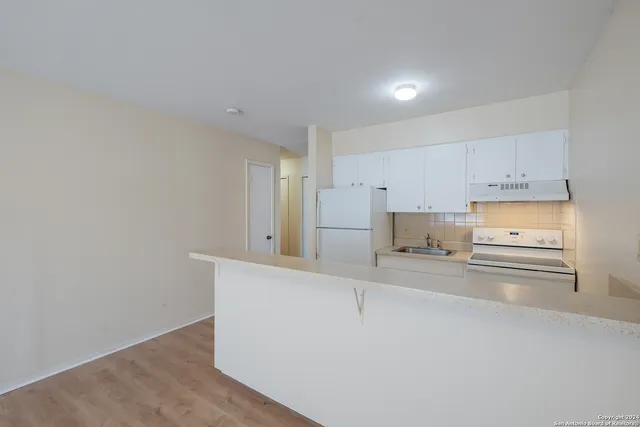 a kitchen with stainless steel appliances a refrigerator and white cabinets