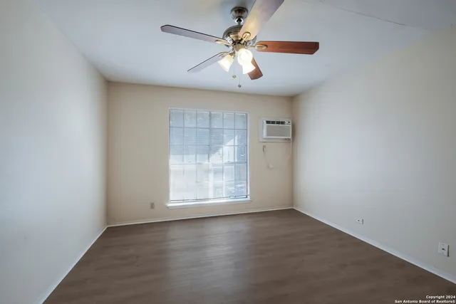 an empty room with windows and chandelier fan