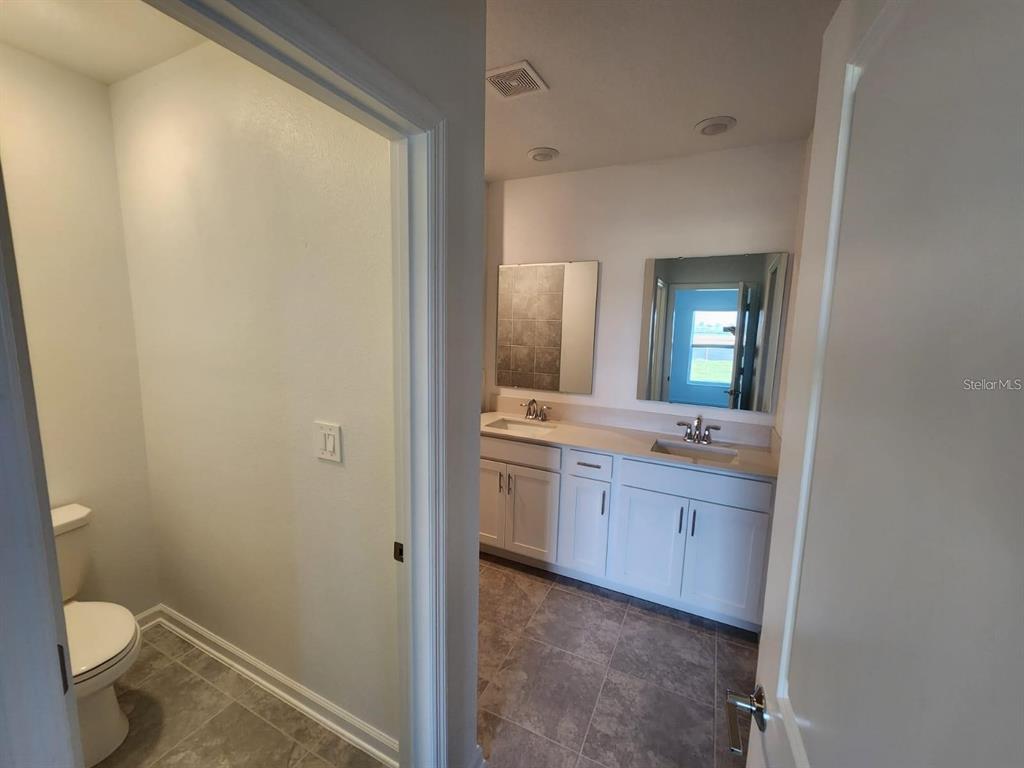 2713 Runners Circle Clermont, FL 34714 - Photo 22 of 30 a bathroom with a granite countertop sink mirror vanity and toilet