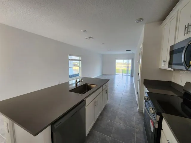 a kitchen with granite countertop a stove a sink and a refrigerator