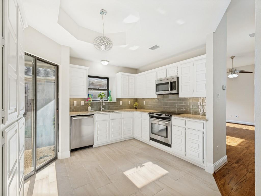 4010 Rive Lane Addison, TX 75001 - Photo 7 of 25 a kitchen with granite countertop stainless steel appliances and white cabinets