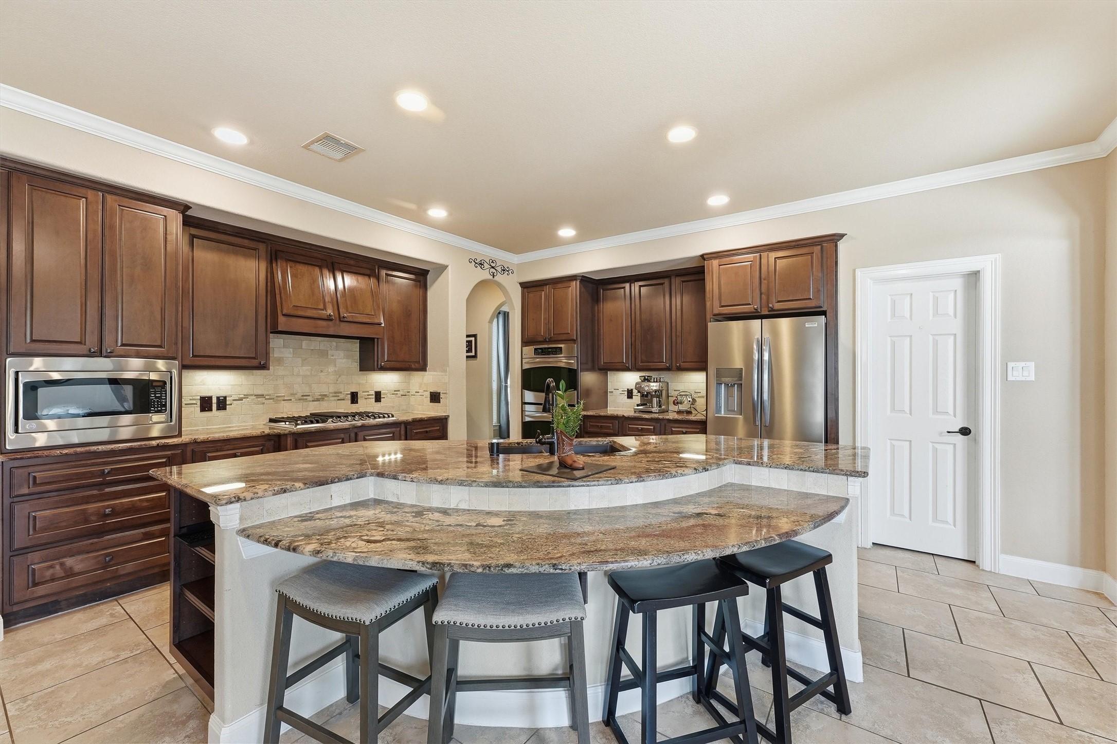 17710 Rough River Court Humble, TX 77346 - Photo 7 of 38 This kitchen features rich wooden cabinetry, a large granite island with seating, stainless steel appliances, and recessed lighting, creating a warm and inviting space for cooking and entertaining.