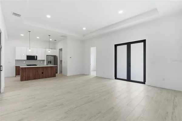 a view of an empty room with a window and kitchen view