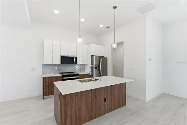 a kitchen with stainless steel appliances a refrigerator a sink a stove and microwave