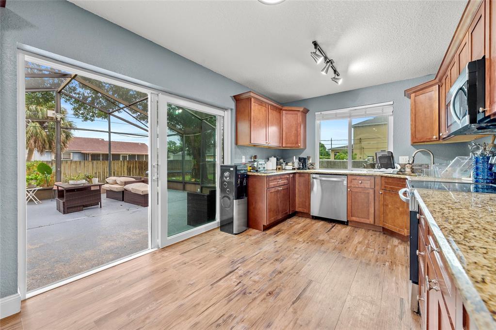 1041 Southwest General Patton Terrace Port St. Lucie, FL 34953 - Photo 11 of 39 a kitchen with stainless steel appliances granite countertop a stove top oven a sink dishwasher a dining table and chairs with wooden floor