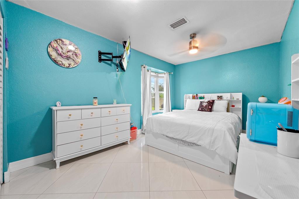 1041 Southwest General Patton Terrace Port St. Lucie, FL 34953 - Photo 18 of 39 a bedroom with a bed and a chandelier