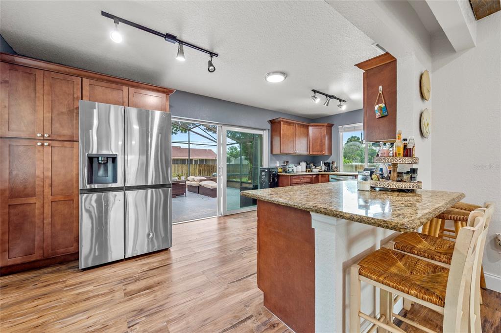 1041 Southwest General Patton Terrace Port St. Lucie, FL 34953 - Photo 9 of 39 a kitchen with stainless steel appliances granite countertop a refrigerator a stove and a sink with wooden floors